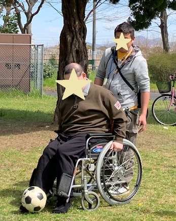 車椅子の男性がサッカーボールを蹴っている