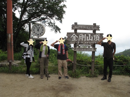 「金剛山頂」の標示の前にて、参加者4人で記念撮影。