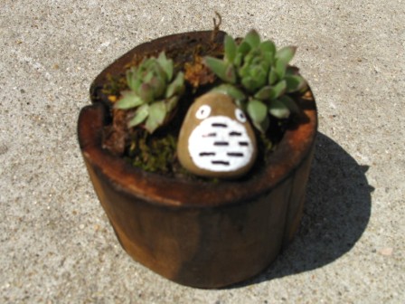 焼いた円筒形の木の鉢に、ヤネバンダイソウ・苔とト◯ロ風に彩色した小石「トロちゃん」の寄せ植え